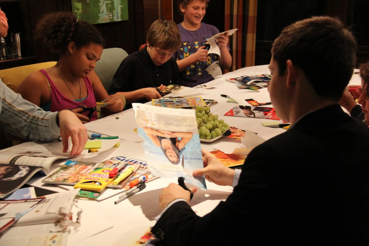 Kids cutting up magazines around a table during the Kurbo participatory design workshop